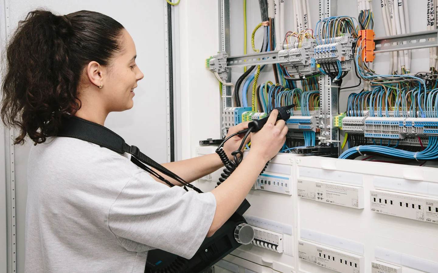 E-CHECK - Mitarbeiterin prüft im Schaltschrank mit einem Meßgerät &middot; W.S. Elektro